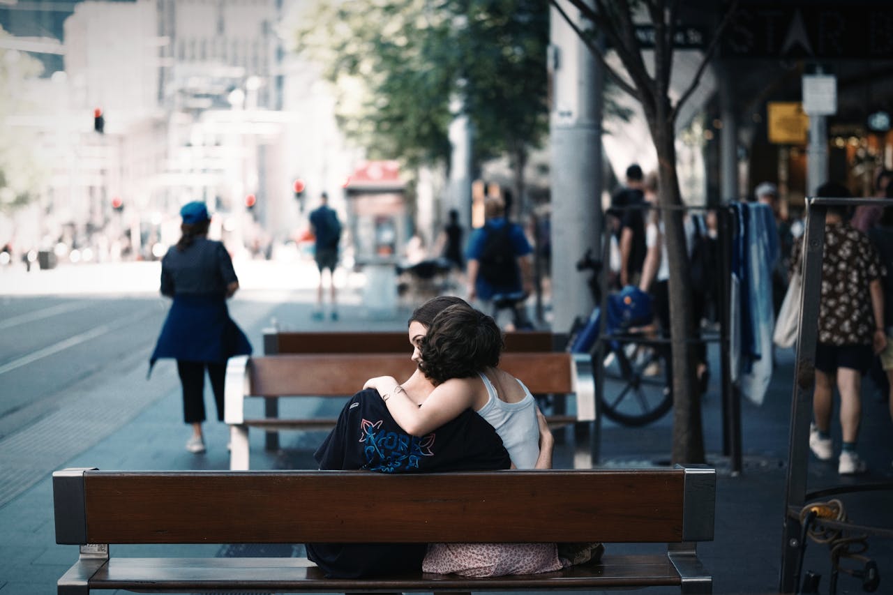services-01 A couple shares an affectionate embrace on a bench in Sydney's bustling city center.